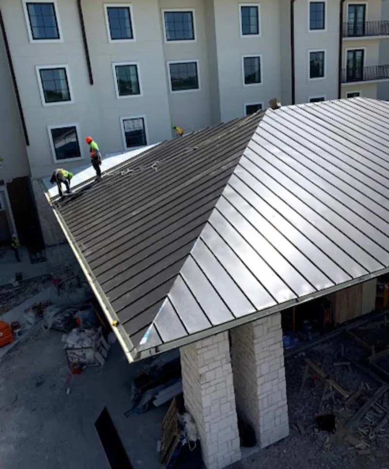 Crew installing standing seam metal roof panels on a commercial project in Bronxville